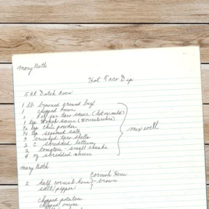 A handwritten recipe on lined notebook paper featuring “Hot Taco Dip” and part of a second recipe for Cornish Hens. The title, ingredients, and directions are written in neat cursive under the name “Mary Beth.”